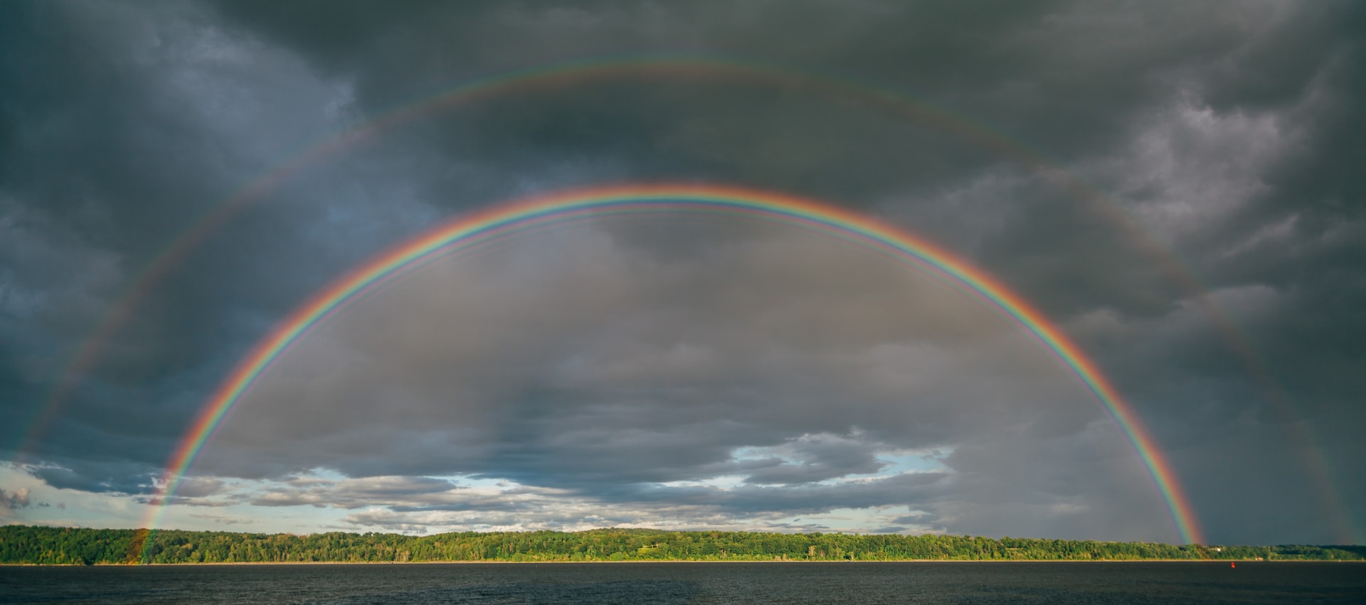 Arco íris sobre floresta e céu tempestuoso