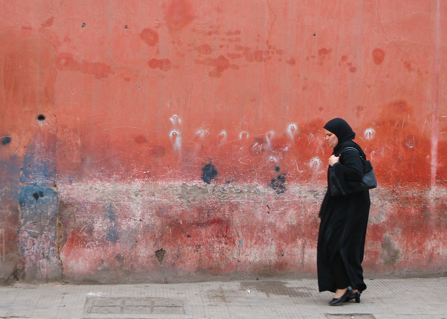 Mulher caminhando em frente a um muro cor salmão